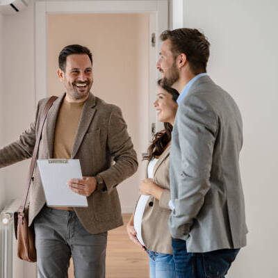 Young married couple talking with a real-estate agent visiting apartment for sale or for rent. Future parents buying an apartment. Real estate concept. A new beginning